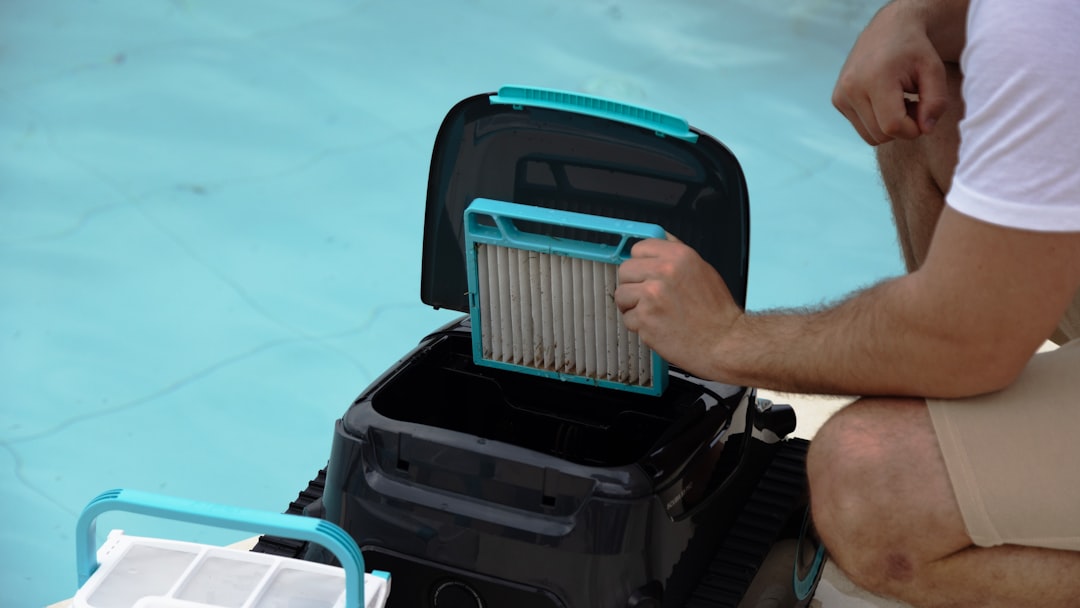 A person removes the filter cartridge from an Aiper pool robot, showcasing easy maintenance design.